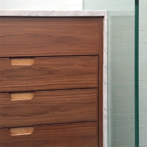New Walnut and Carrara marble vanity beside glass shower panel